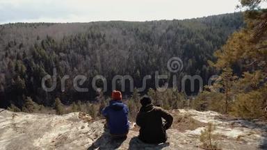 游客夫妇坐在岩石上看针叶林。 日落<strong>时</strong>分<strong>远离</strong>家乡的冒险
